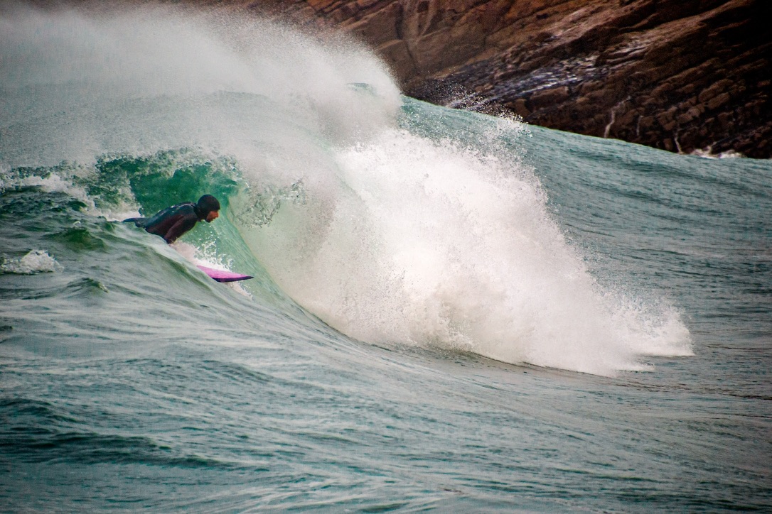 Surfeur engagé dans une vague puissante devant la falaise